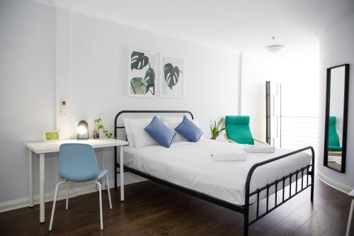 um quarto com uma cama, uma secretária e uma cadeira azul em Loft-Style Living - Sophisticated Urban Retreat em Sydney