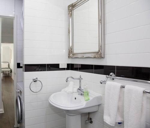 uma casa de banho com lavatório, espelho e toalhas em Loft-Style Living - Sophisticated Urban Retreat em Sydney