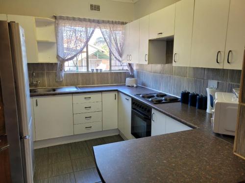 a kitchen with white cabinets and a stove top oven at 29B Zebra Street - InHimwe Guesthouse in Polokwane