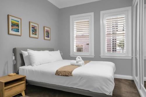 een slaapkamer met een wit bed met een knuffeldier erop bij 'Beachside Bliss' Heart of the Coastal Lifestyle in Sydney