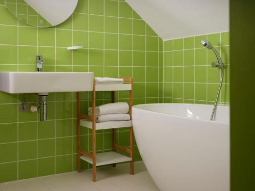 La salle de bains est pourvue d'un lavabo, d'une baignoire et de carrelage vert. dans l'établissement Cité des Électriciens, à Bruay-la-Buissière
