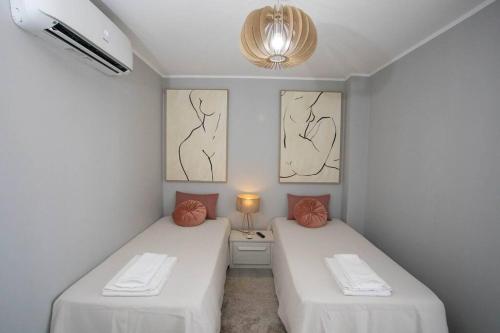 two beds in a room with white sheets and orange pillows at Apartamento Janelas da Ria in Faro