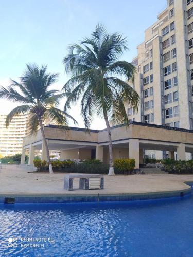 a building with palm trees in front of a swimming pool at Margarita & More, Omas in Porlamar