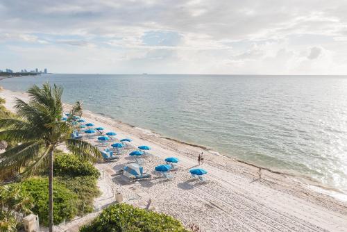 a beach with blue umbrellas and chairs and the ocean at Gorgeous Partial Ocean View I The Ritz Carlton in Miami
