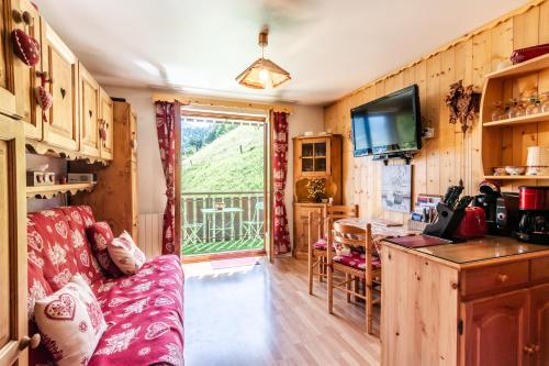 a living room with a red couch and a television at Le Petit Aulps - Studio avec vue montagne in Saint-Jean-d'Aulps