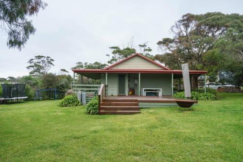 a small house with a porch on a grass field at 'Flinders Cabin' A Cosy Family Beach Shack in Flinders