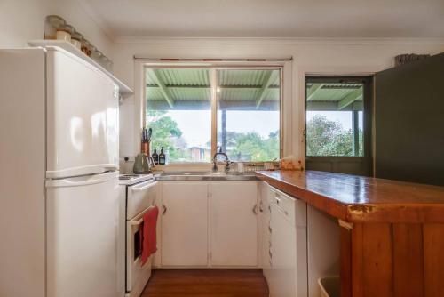 a kitchen with a white refrigerator and a sink at 'Flinders Cabin' A Cosy Family Beach Shack in Flinders