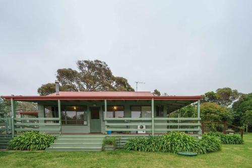 a house with a red roof on a grass field at 'Flinders Cabin' A Cosy Family Beach Shack in Flinders