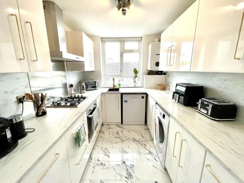 a white kitchen with white cabinets and appliances at Beautiful 3-bed apartment at Swiss Cottage in London