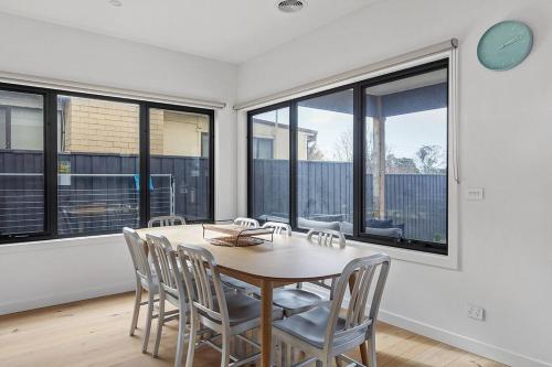 a dining room with a table and chairs and windows at Contemporary Coastal Escape with Sparkling Pool in Rosebud