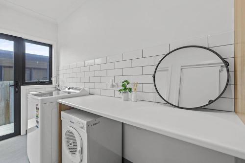 a white bathroom with a sink and a mirror at Contemporary Coastal Escape with Sparkling Pool in Rosebud
