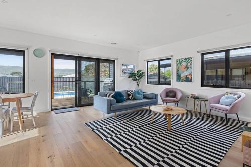 a living room with a couch and chairs and a table at Contemporary Coastal Escape with Sparkling Pool in Rosebud