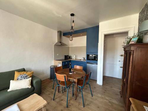 een woonkamer met een tafel en een groene bank bij Gîte « Le Marie » in Saint-Martin-aux-Buneaux