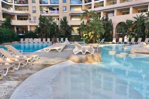 une piscine avec des chaises longues et un hôtel dans l'établissement WOW* mer/piscine/climat/parking, à Cannes