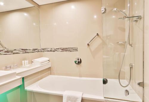 a bathroom with a shower and a tub and a sink at Holiday Inn Johannesburg-Rosebank by IHG in Johannesburg
