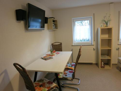 Habitación con mesa y TV en la pared. en Ferienwohnung Schlesinger, en Hohnstein