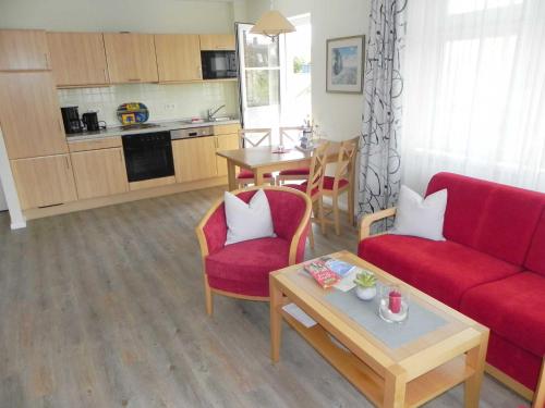 ein Wohnzimmer mit einem roten Sofa und einem Tisch in der Unterkunft Ferienwohnung 3 26 Inselstrand in Ahlbeck
