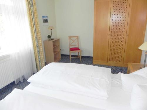 ein Schlafzimmer mit einem weißen Bett und einem roten Stuhl in der Unterkunft Ferienwohnung 3 26 Inselstrand in Ahlbeck