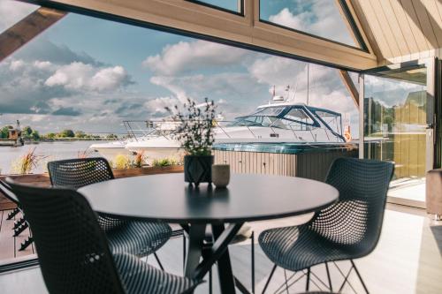 a table and chairs on a balcony with a boat at Ostas Mājas in Engure