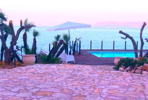 eine Terrasse mit einem Sonnenschirm und einem Pool in der Unterkunft Il Casale San Vito in San Vito lo Capo