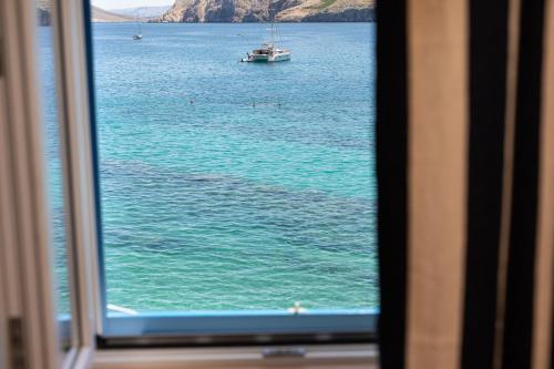 una ventana con vistas al océano con un barco en el agua en Little beach house, en Baška