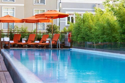 una piscina con sombrillas naranjas, mesas y sillas en Park Hyatt Istanbul - Macka Palas en Estambul