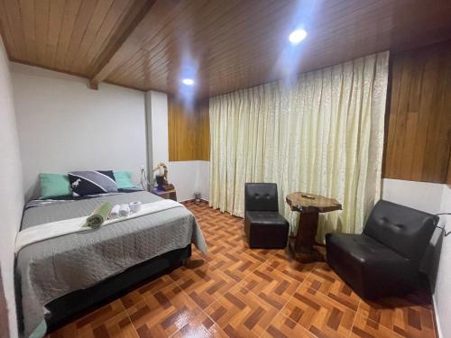 a bedroom with a bed and two chairs at Paz y Bien in Villa Rica