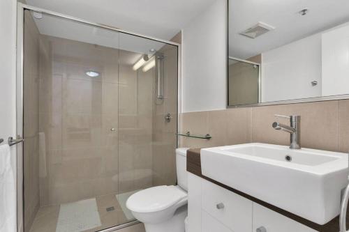 Un baño con inodoro, lavabo y ducha. en Coastal Chic in Heart of Cairns with Rooftop Pool, en Cairns