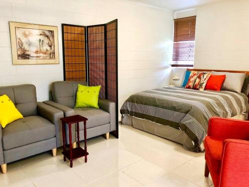 una camera con letto, divano e sedia di Coastal Living near Shops and Botanical Gardens a Edge Hill