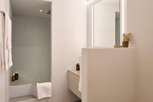 a white bathroom with a mirror and a sink at Casa Mulania in Laax