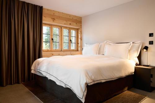 a bedroom with a large white bed with a window at Casa Mulania in Laax