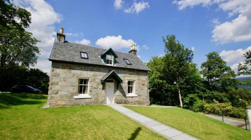 an old stone house on a green lawn at Edinample Lodge in Lochearnhead