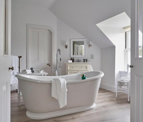 a white bathroom with a tub and a sink at Achnahatnich House in Aviemore