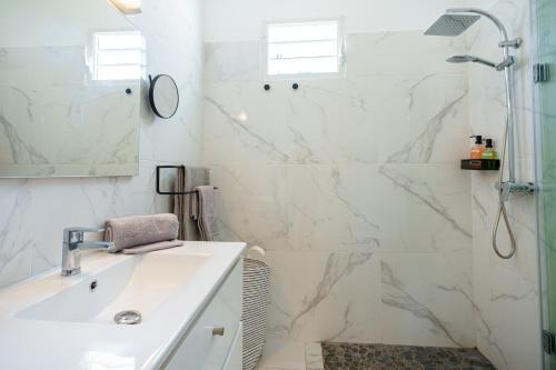 baño blanco con ducha y lavamanos en Villa des Pentas – Chaleureuse Villa moderne avec piscine, en Baie-Mahault