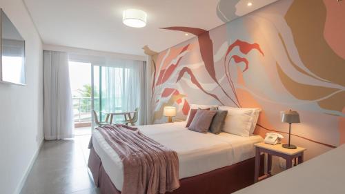 a bedroom with a bed with a painting on the wall at Kembali Hotel Porto de Galinhas - Adults Only in Porto De Galinhas