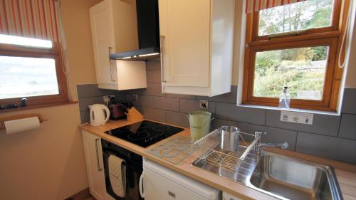 a kitchen with a sink and a stove top oven at Morenish Mews Killin Cottage in Morenish