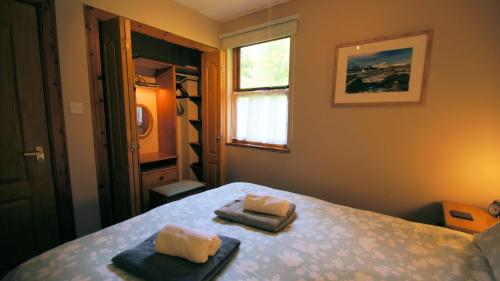 a bedroom with two towels sitting on a bed at Morenish Mews Killin Cottage in Morenish