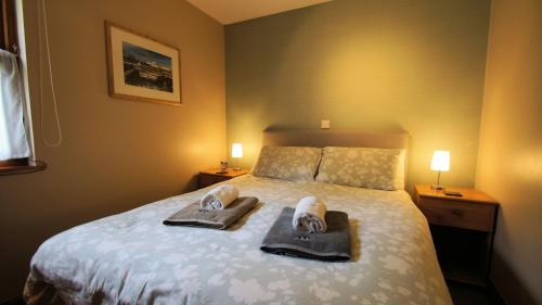 sypialnia z łóżkiem z ręcznikami i butami w obiekcie Morenish Mews Kenmore Cottage w mieście Morenish