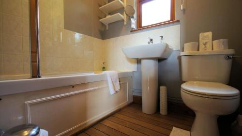 a bathroom with a toilet and a sink and a tub at Morenish Mews Kenmore Cottage in Morenish