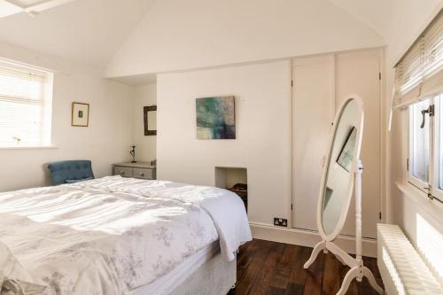 a white bedroom with a bed and a mirror at Beautiful little Townhouse situated in Brighton's Regency Conservation Area in Brighton & Hove