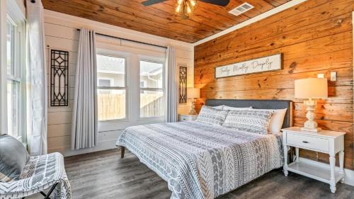 a bedroom with a bed and a wooden wall at Curated Cottage. minutes from Silos, zoo, Baylor in Waco