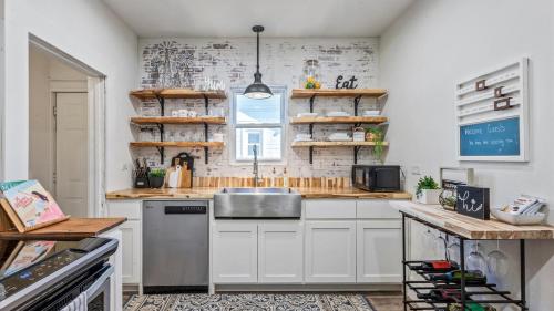 a kitchen with white cabinets and a sink and a window at Curated Cottage. minutes from Silos, zoo, Baylor in Waco