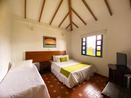 a bedroom with two beds and a television in it at Ecohotel La Casona in Pereira