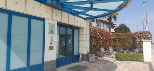 un bâtiment avec des portes et des chaises bleues sur un trottoir dans l'établissement Hotel Ceretto, à Busca