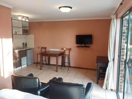 a living room with a table and chairs and a tv at Kwena Maribane Lodge in Erasmus
