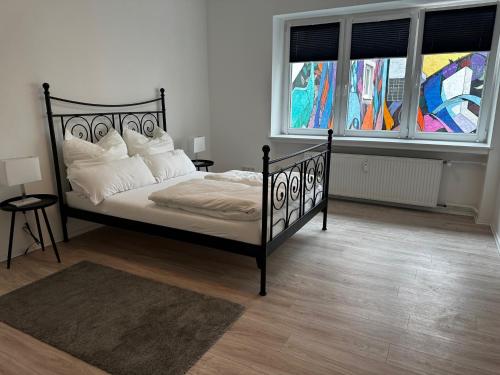 1 Schlafzimmer mit einem schwarzen Bett und 2 Fenstern in der Unterkunft Wohnung am Marktplatz in Gießen