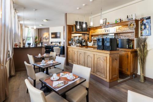 un restaurante con mesas y sillas y un bar en Hotel des Ducs, en Alençon