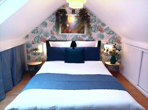 a bedroom with a blue and white bed with two tables at Le Duplex Décontracté in Fleury-les-Aubrais