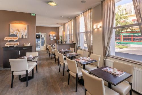 a restaurant with tables and chairs and a window at Hotel des Ducs in Alençon