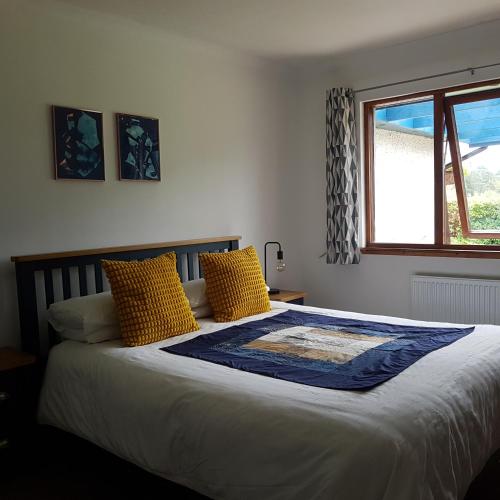 a bedroom with a bed with yellow pillows and a window at Beech House in Fort William